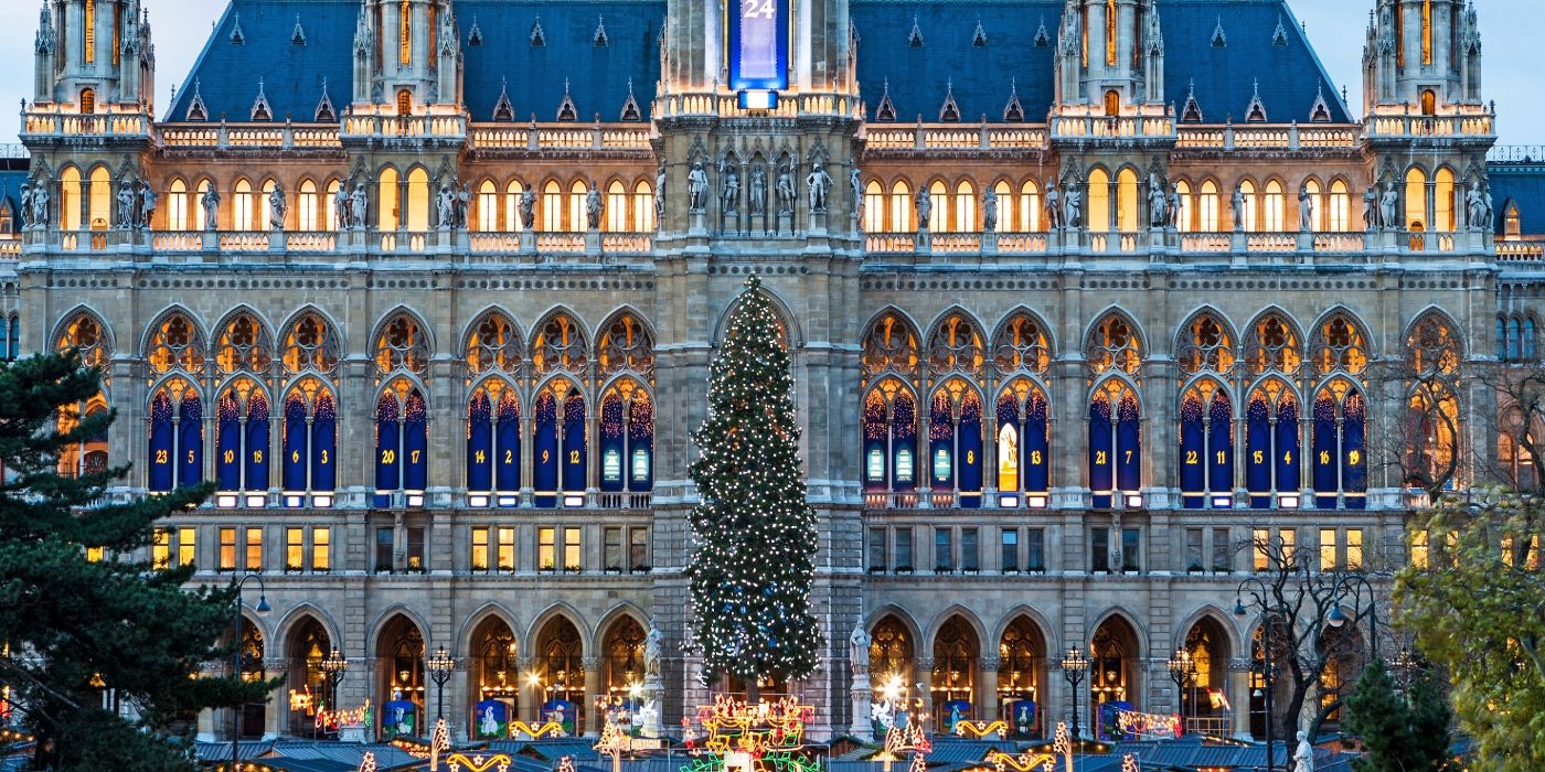 Christmas tree in front of Vienna's Parliament Building, adorned with colorful lights and ornaments.