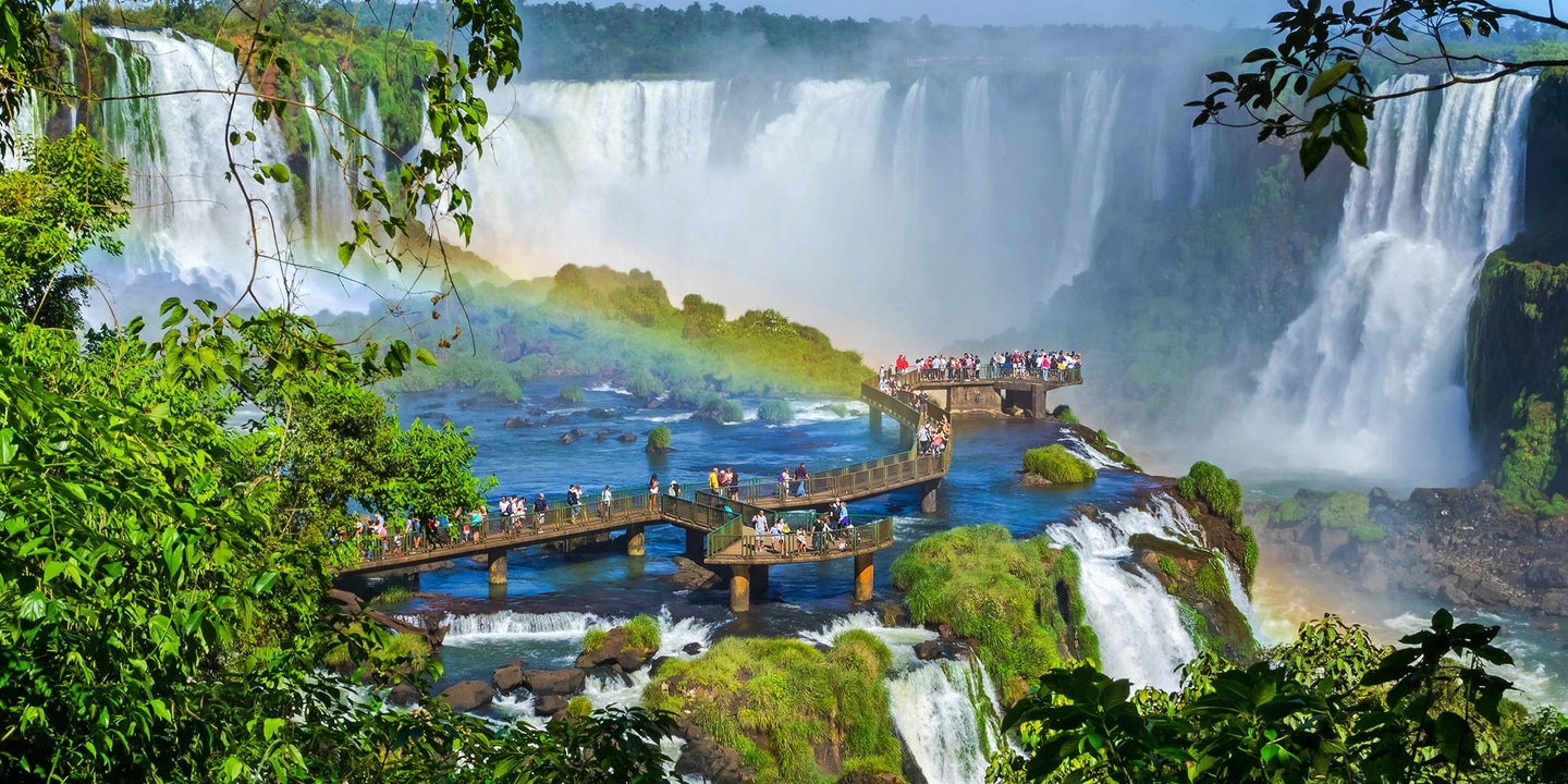 Boardwalk lookout over Iguazú Falls with rainbow and lush rainforest