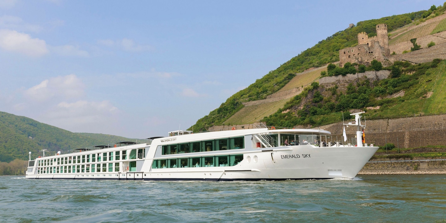 Luxury river cruise ship sailing next to a cliff with a castle on it
