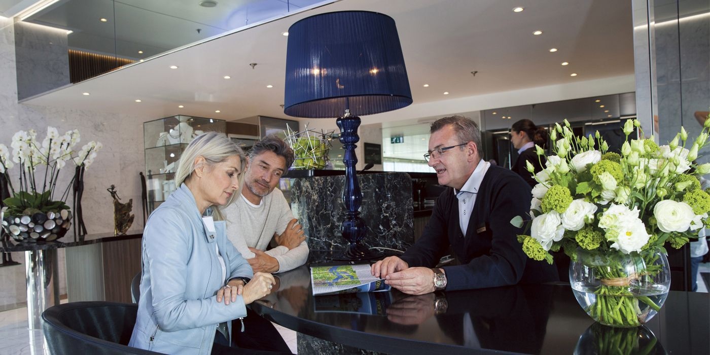 Guests at reception desk with Scenic Cruise Director